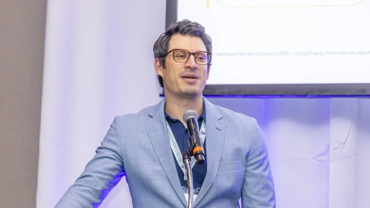 Speaker presenting on stage at the BMA Smart Healthcare Facilities Convention in Houston, September 2026